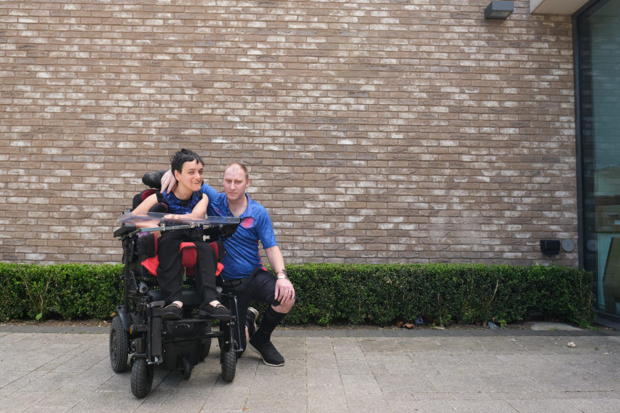 a man is kneeling next to a woman in a wheelchair on the pavement