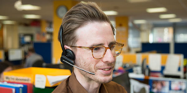 A man wearing a headset and glasses with suitably coiffed hair