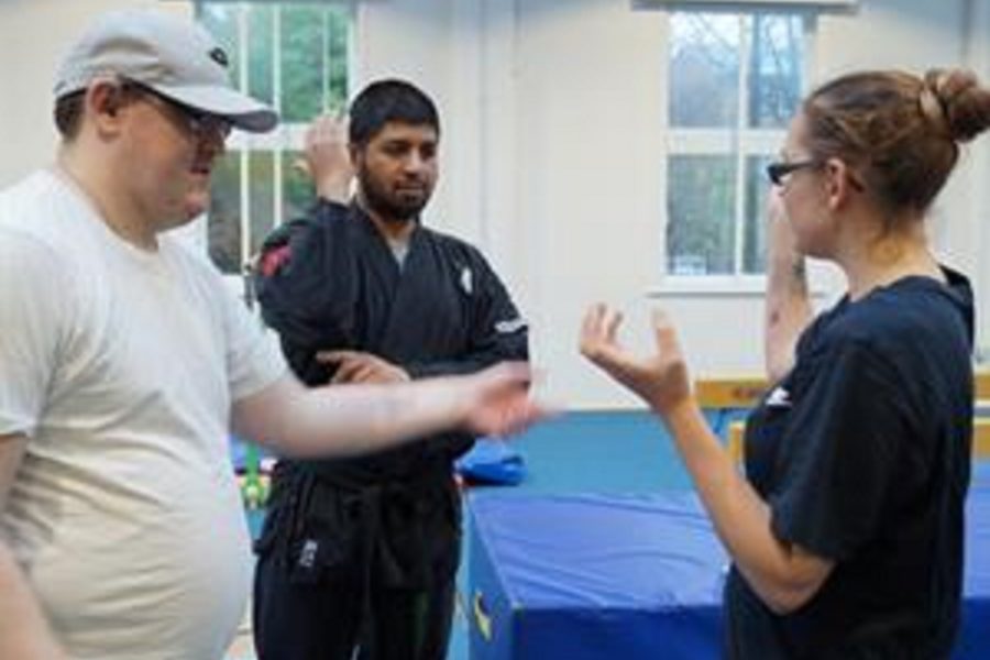 One instructor helping a middle aged man and women perform tai chi