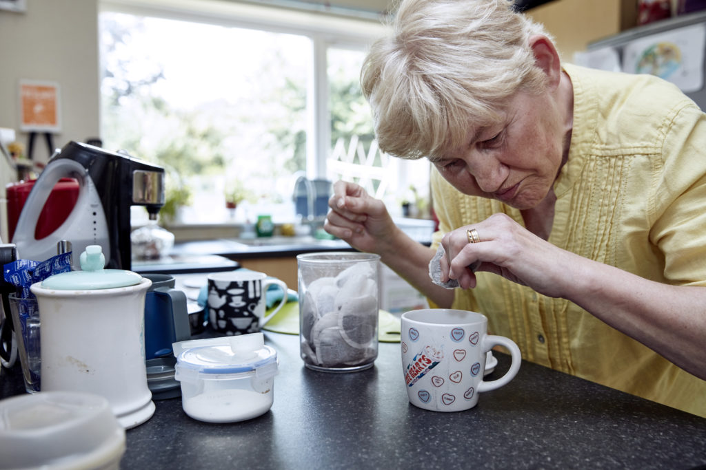 Lin, a woman with short grey hair, making a cup of tea in her supported living home in Exeter.