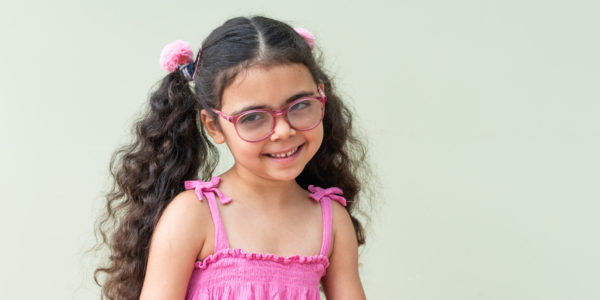 Remi, a young girl with long pigtails and glasses, smiling at the camera.
