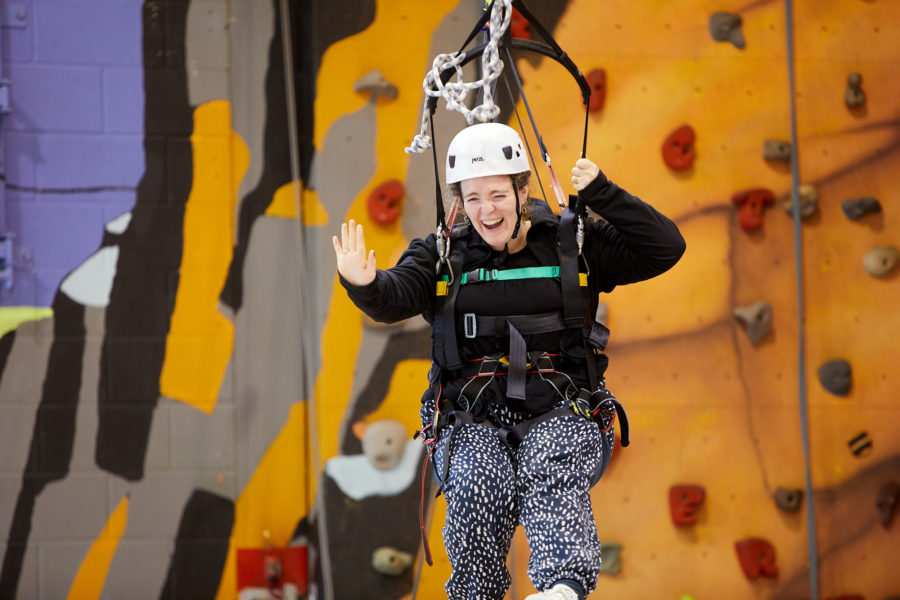 A young woman wearing a climbing rig smiling