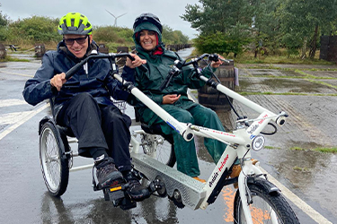 A man and a woman on a two seated bike in the rain