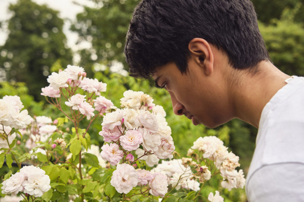 A young boy smells some flowers.