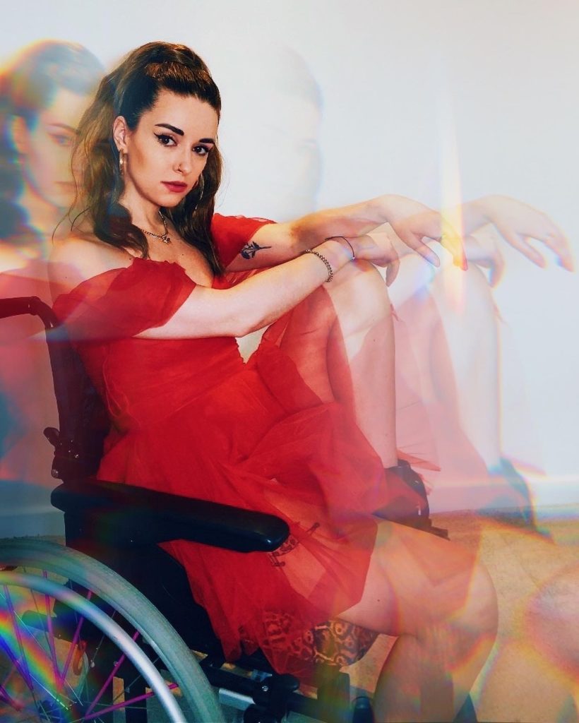 Alice Ella, a white woman wearing a red dress in a wheelchair.