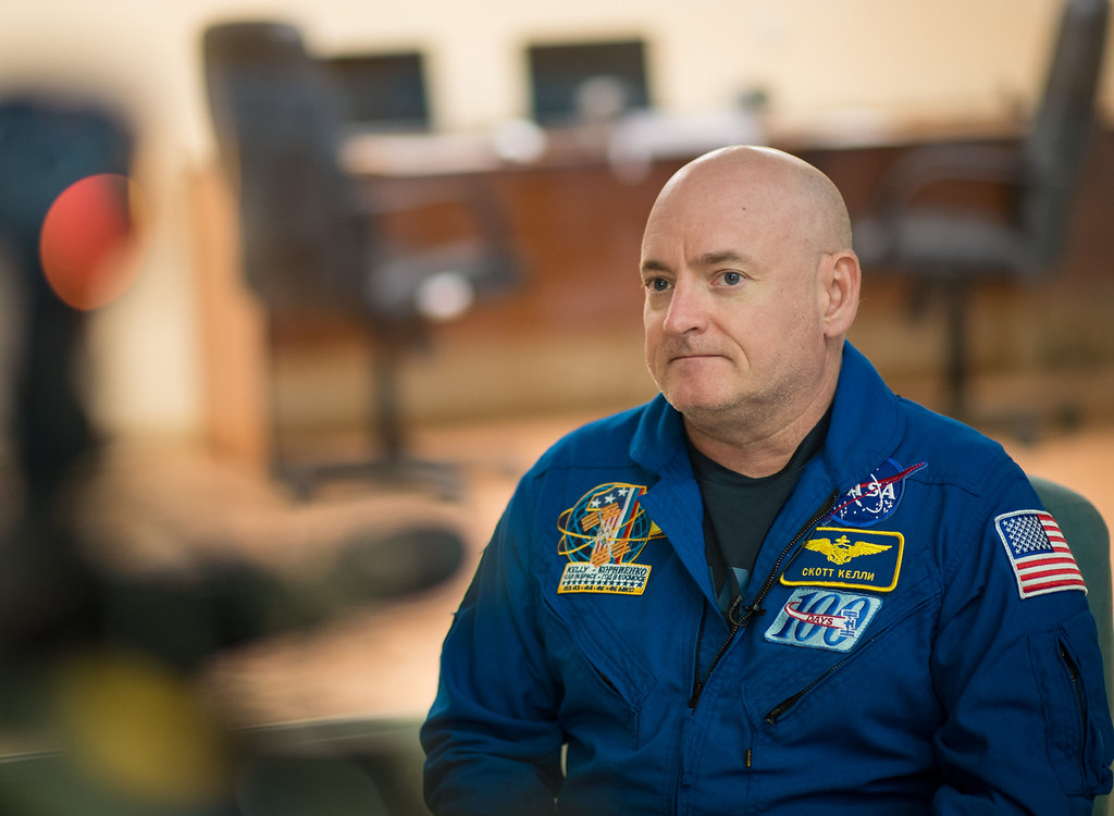 Scott Kelly, a bald man wearing a blue NASA uniform.