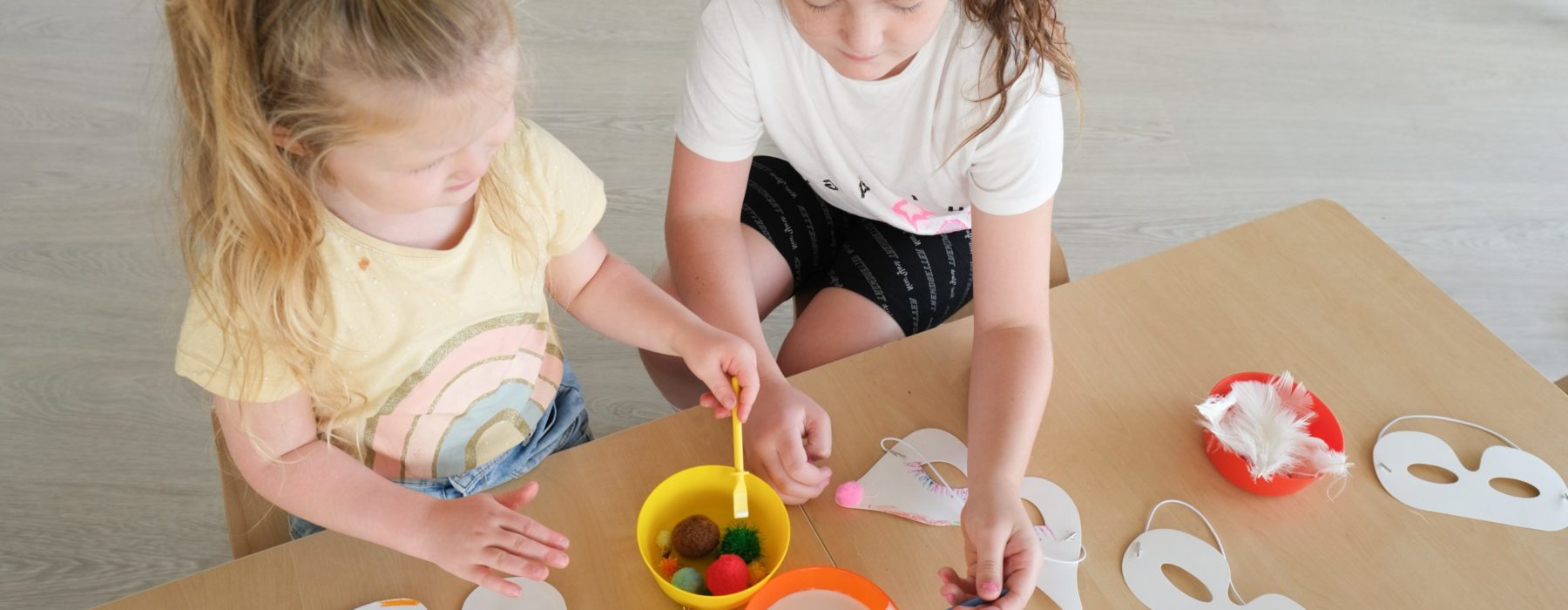 two young children are painting on a table while stiting down