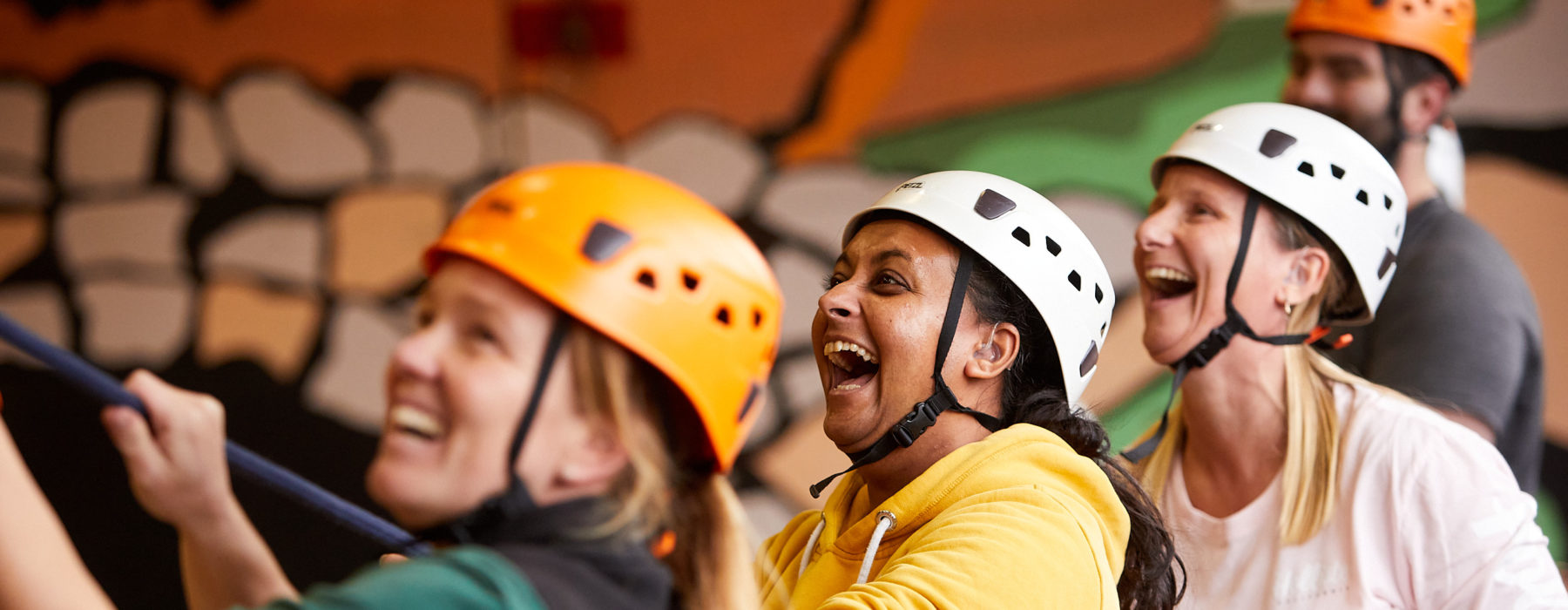 A group of people in helmets smile and hold a rope