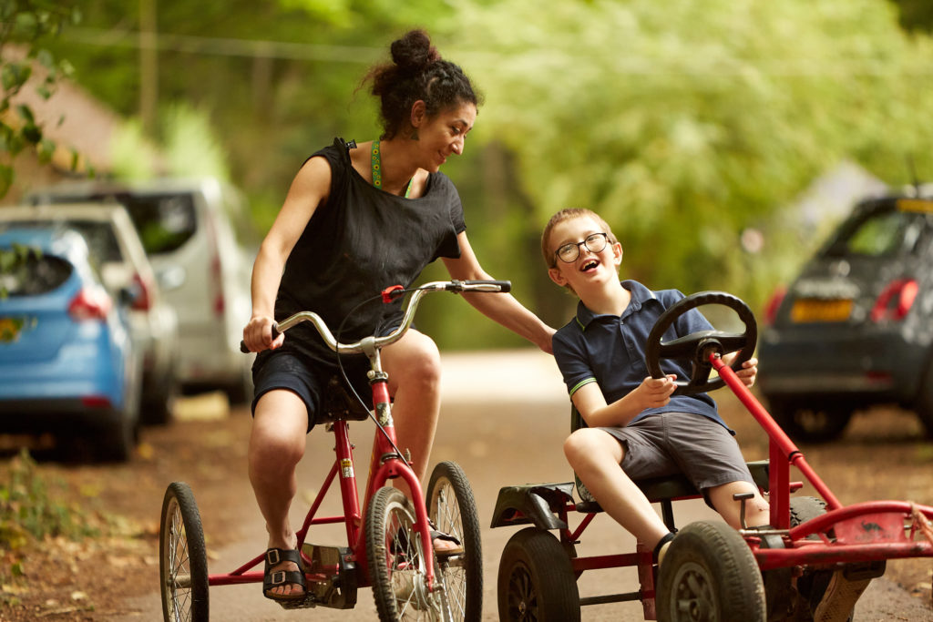 A woman on a tricycle and a boy on a gocart