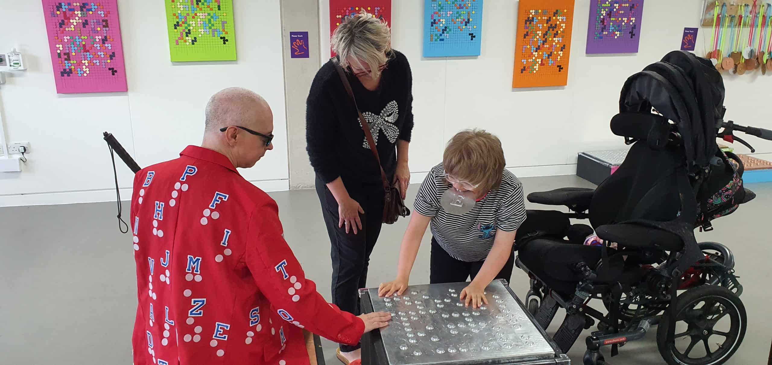 A young woman reading braille with a man and a woman