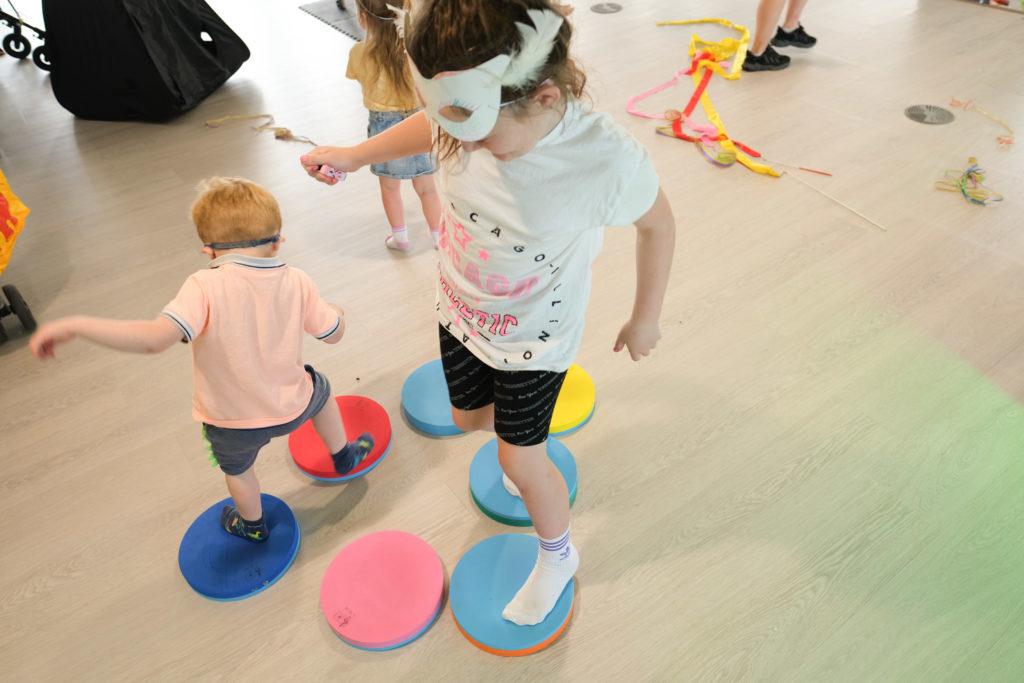 Children standing on colourful circles that give sensory feedback in the TouchBase Pears family room.