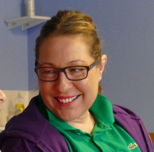 Ruth, a white woman with brown hair and glasses, smiling.