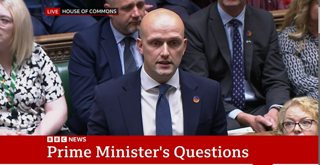 Screenshot of Stephen Flynn MP wearing a Sense badge in parliament.  There is a caption from BBC news that says 'Prime Minister's questions'
