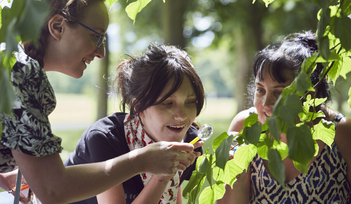 2 woman and a young girl looking at plants in a park