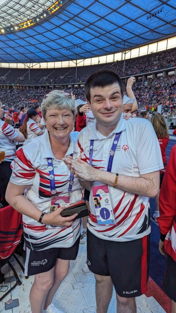 Shirley and her son Dan, both wearing Special Olympics t-shirts and medals and smiling happily for the camera.