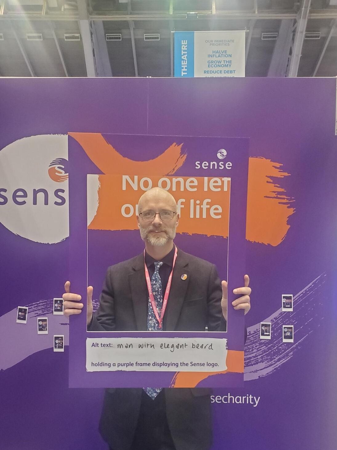 Michael, a man with a beard, holding a purple frame saying ‘man with elegant beard holding a purple frame displaying a Sense logo’ he is in front of a purple background with the Sense logo on