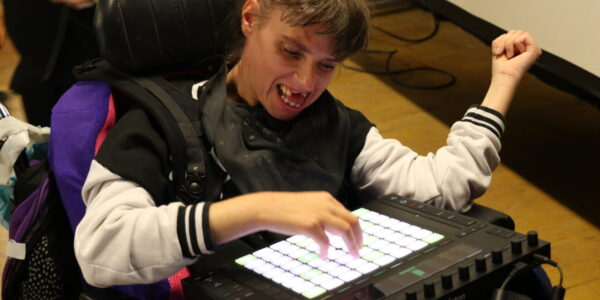 A young woman excitedly draws her hand across an electronic touchpad to play different notes and sounds