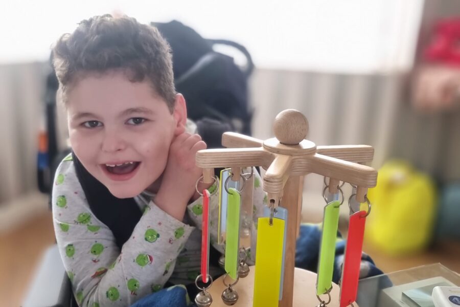A young boy smiling with his "Chimeabout" sensory toy.