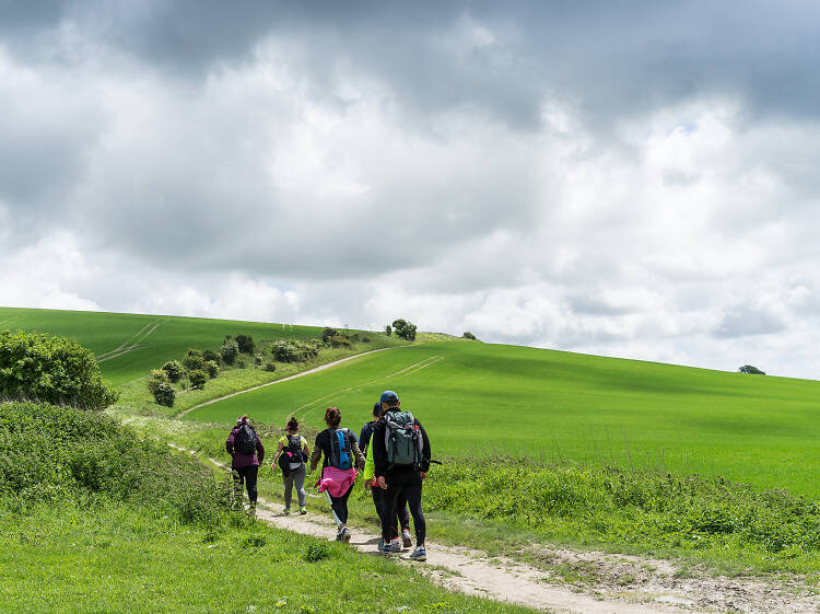 A group of walkers head up a low hill on a cloudy day.