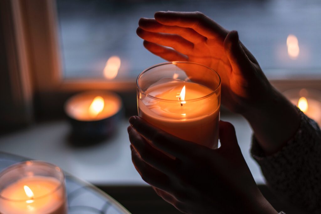 Hands holding a candle, surrounded by other candles.