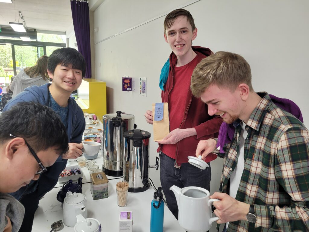 Four young men around a table make tea