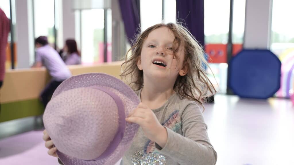 A young blonde girl holding a hat