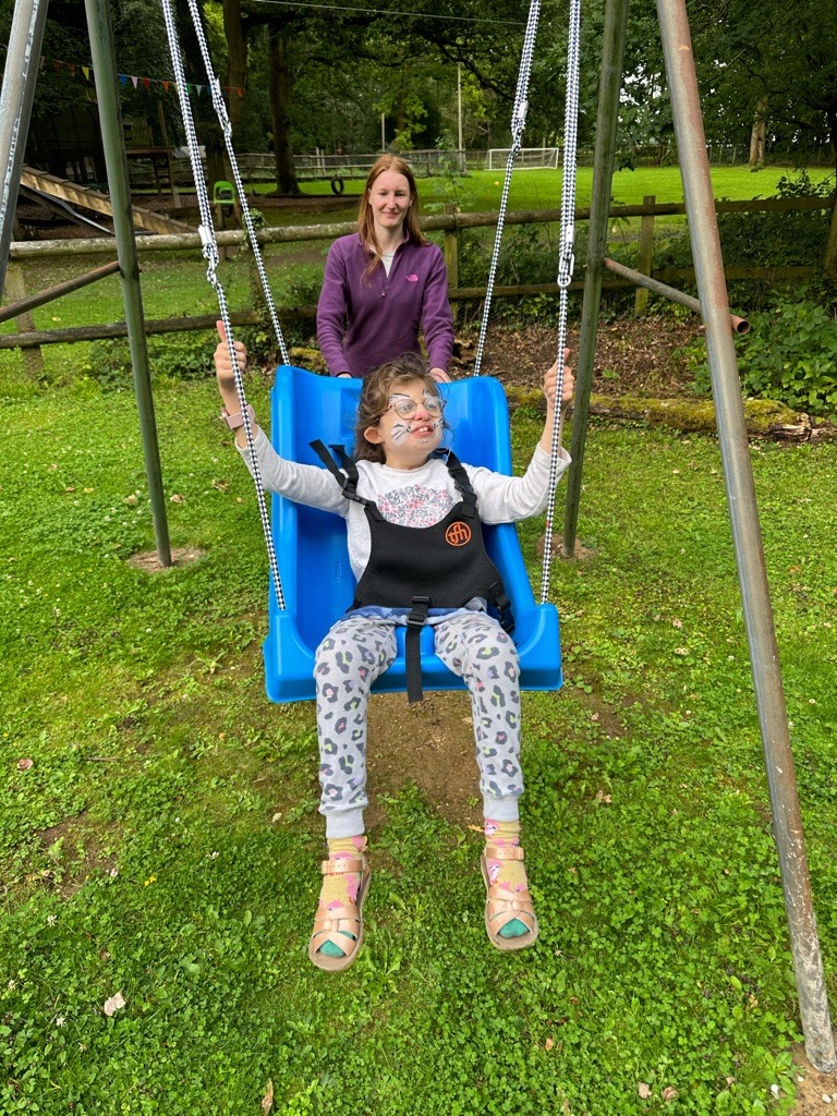 Orla enjoying being pushed in a swing by a Sense Holidays volunteer.