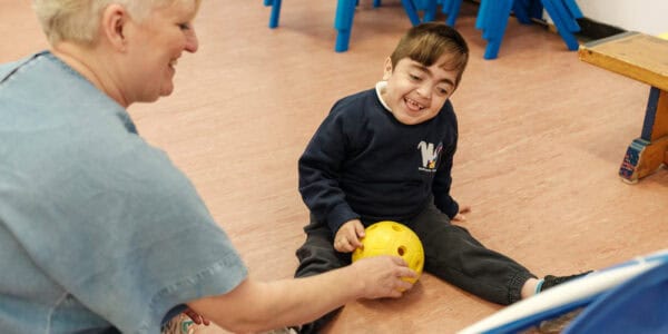 A boy sits on the floor looking at a football