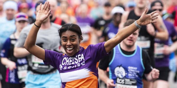 Female London Marathon runner with Sense T-Shirt waving arms at the camera.