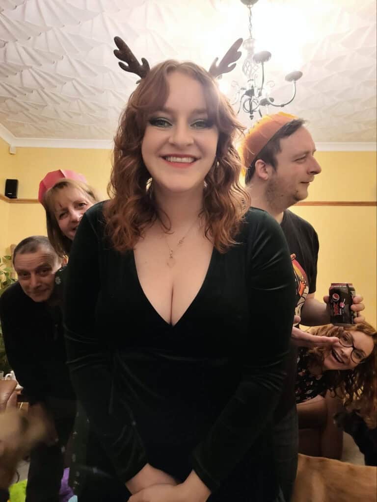 Jeffie celebrating Christmas with family, wearing Rudolph antlers and smiling.
