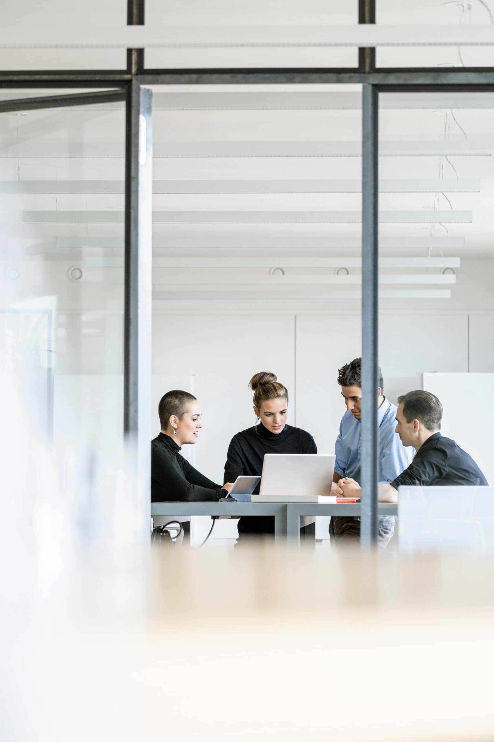 A group of business people gathered around a laptop