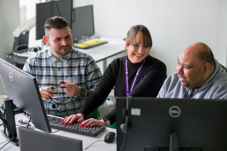 A woman training two men how to use computers