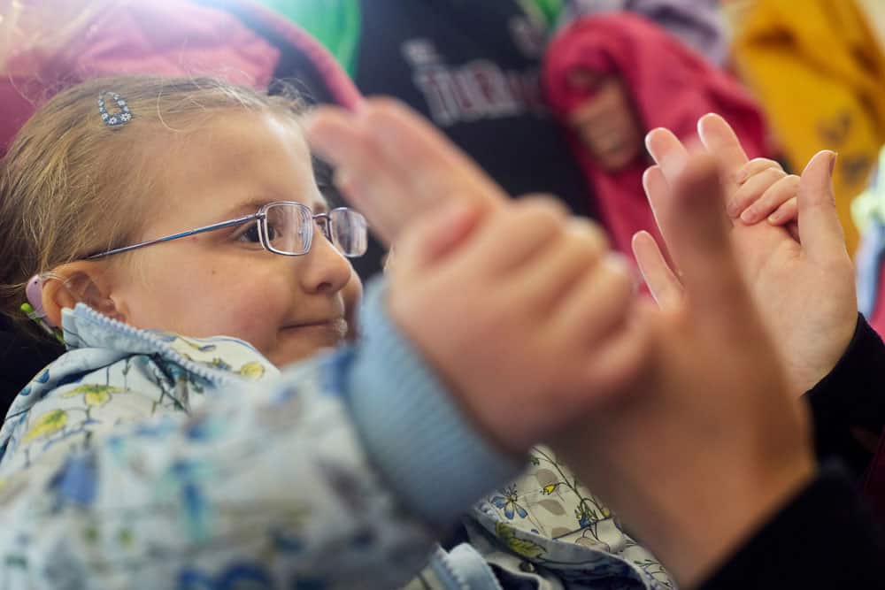 A little girl smiles as she holds an adult's hand
