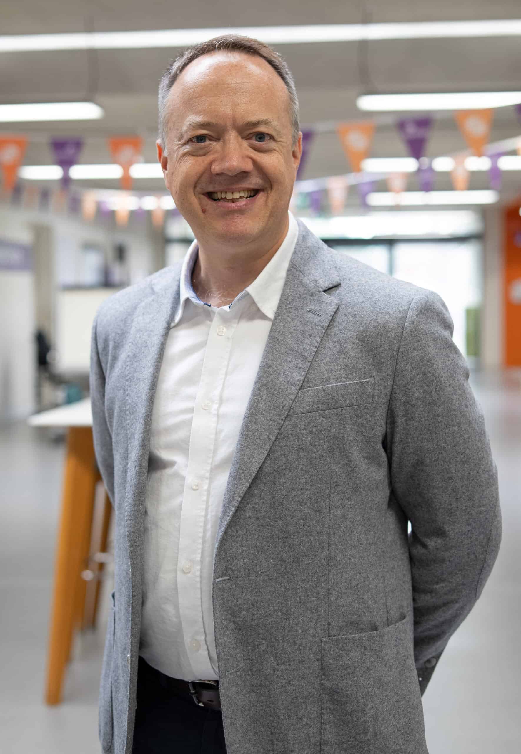 A portrait of a man wearing a smart grey jacket.