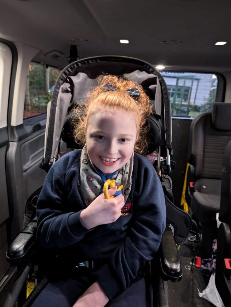 A young redheaded girl smiles in her wheelchair