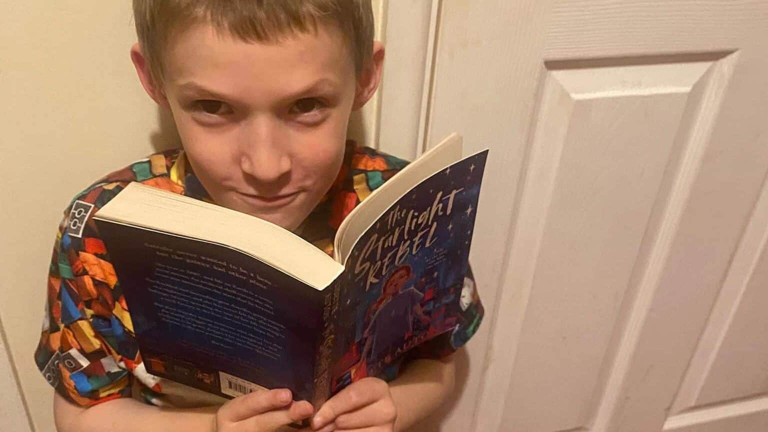 Benjie is holding his copy of The Starlight Rebel, while staring at the camera.