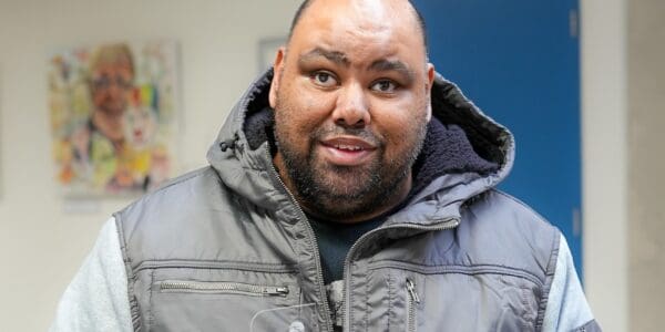 A man smiling as he holds up an award with the Sense logo on it. He is standing in the foyer of Sense TouchBase Pears in Birmingham.