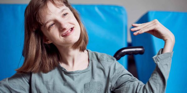 A young girl with brown hair is stretching her hand to her shoulder in a yoga pose