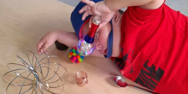 A young boy is leaning over a wooden board, holding a light up orb close to his face in front of him