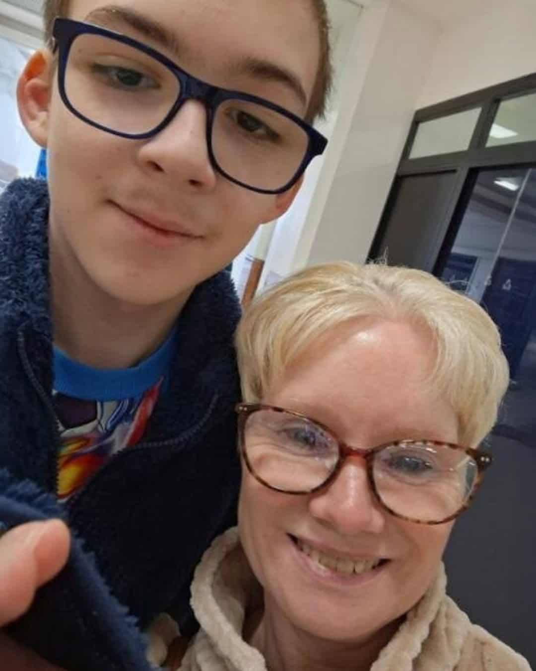 A blonde woman and her teenage son both smile at the camera