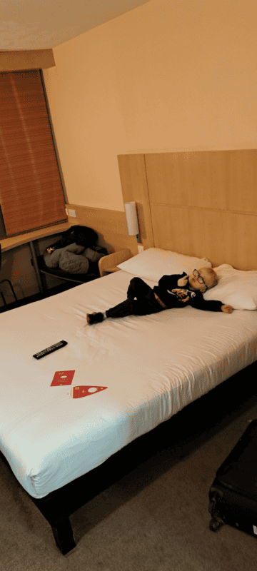 A young boy in a hotel room lying on a large bed