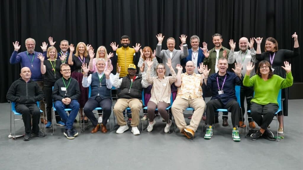 A group of people smile and wave their hands