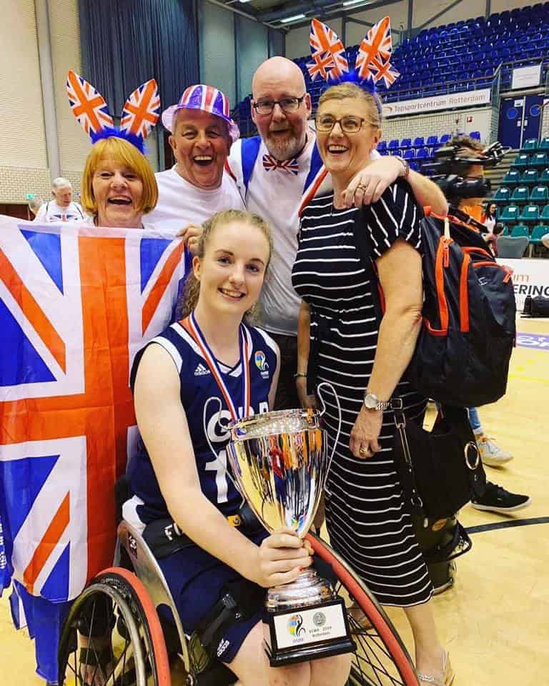 Siobhan is sat in her wheelchair, holding the European Champion Silver Medal Cup - with her parents, auntie and uncle all stood behind covered in the Union Jack.