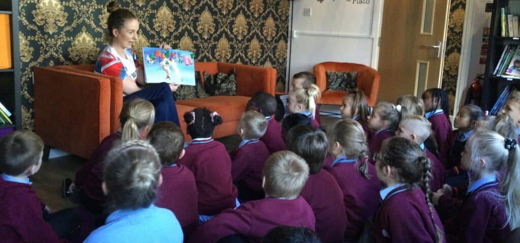 Siobhan is reading a story about differences to a classroom full of students who are sat on the floor an listening attentively.