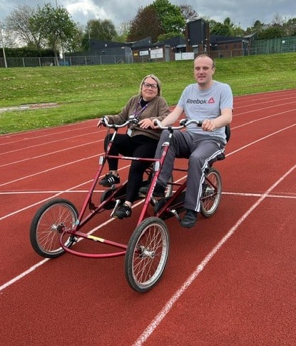 Carl is cycling on a side by side tandem bicycle.