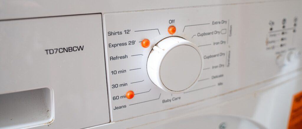 A close up of a washing machines dial with various washing options around it. There are orange Bumpons in key spots so Joe know where certain settings are.