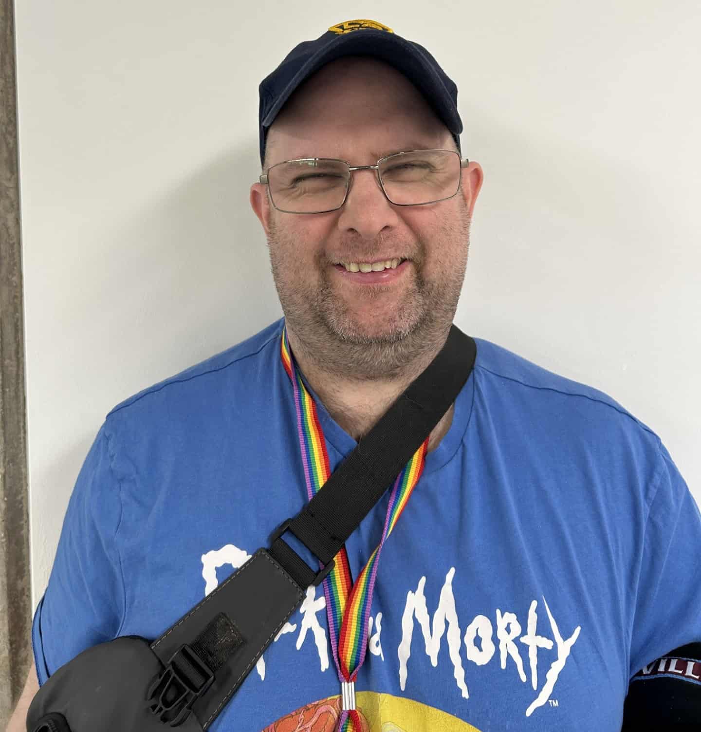 A man wearing a cap, glasses and a blue t-shirt.